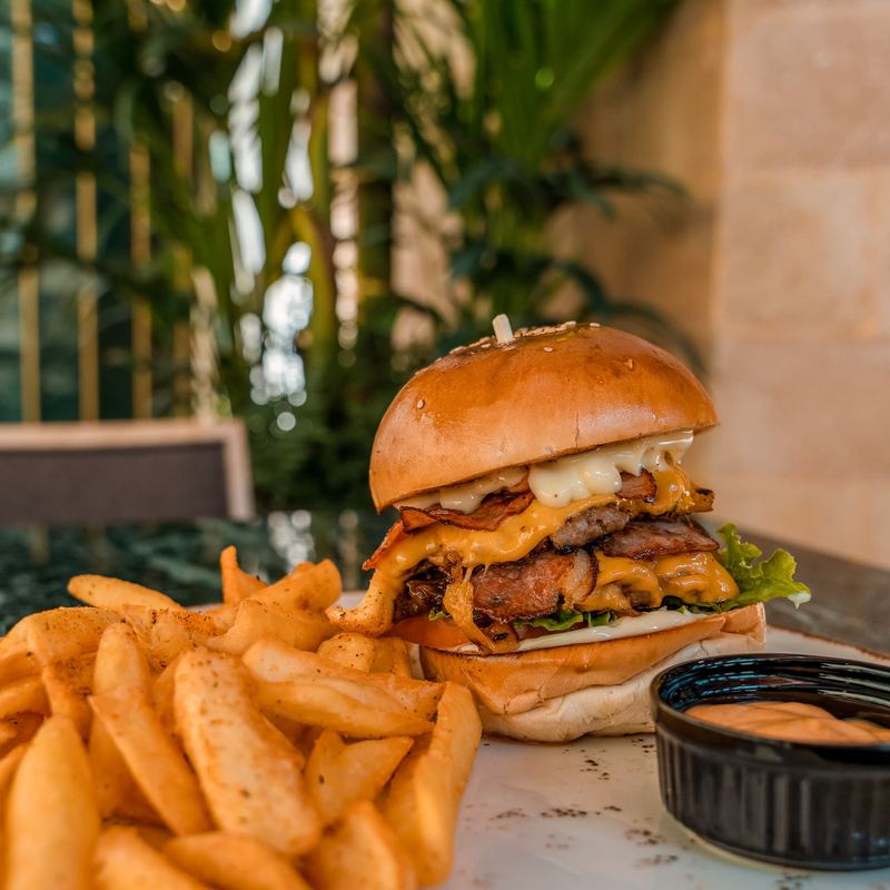 Double smash burger with bacon, melted cheddar and lettuce on a brioche bun, served with crispy potato wedges