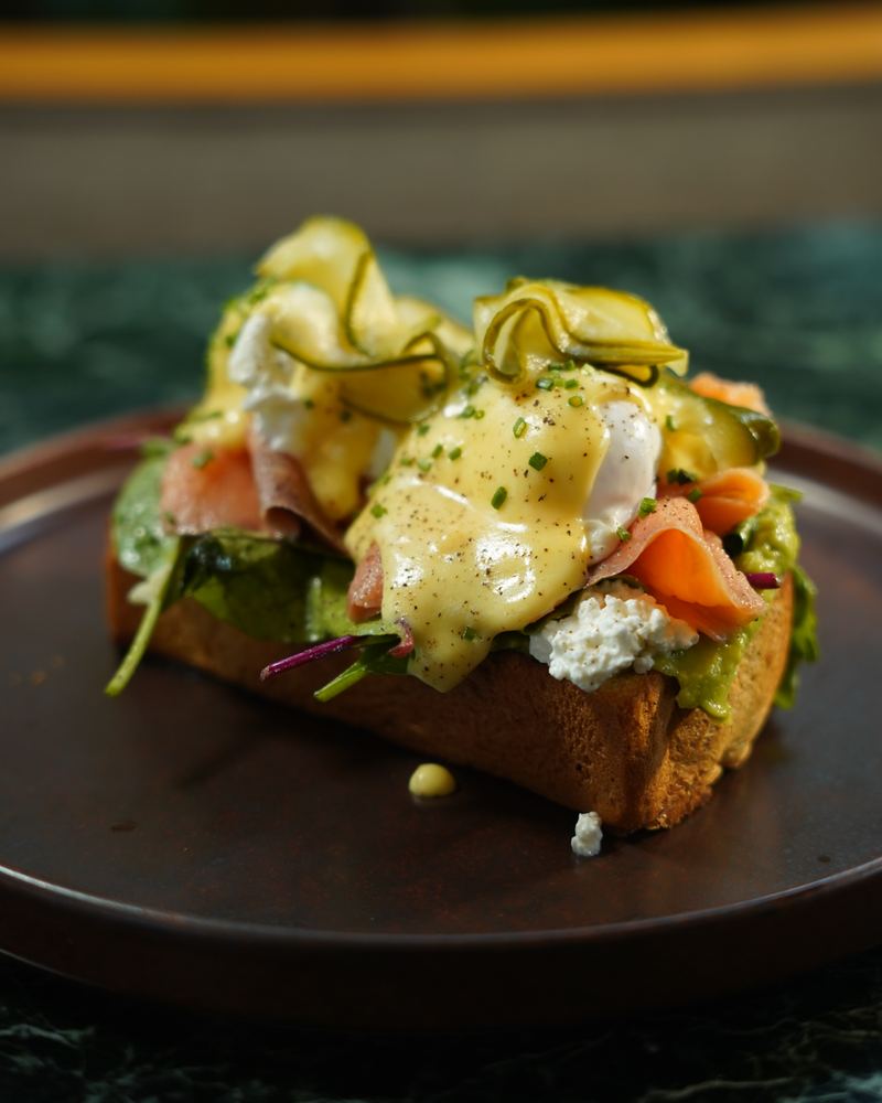 Poached eggs with hollandaise, smoked salmon, avocado, feta and pickled zucchini ribbons on toasted brioche