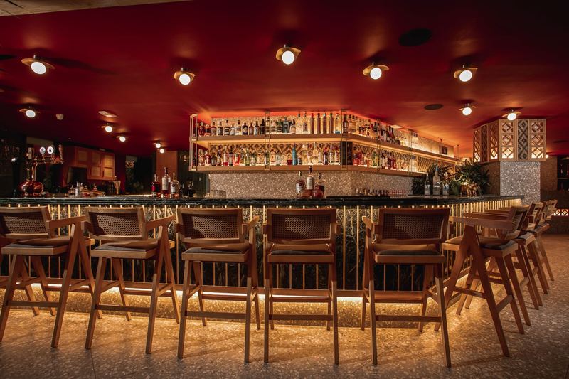 Al Hayat's centre bar lined with wooden stools beneath a crimson ceiling and shelves of premium spirits and liqueurs