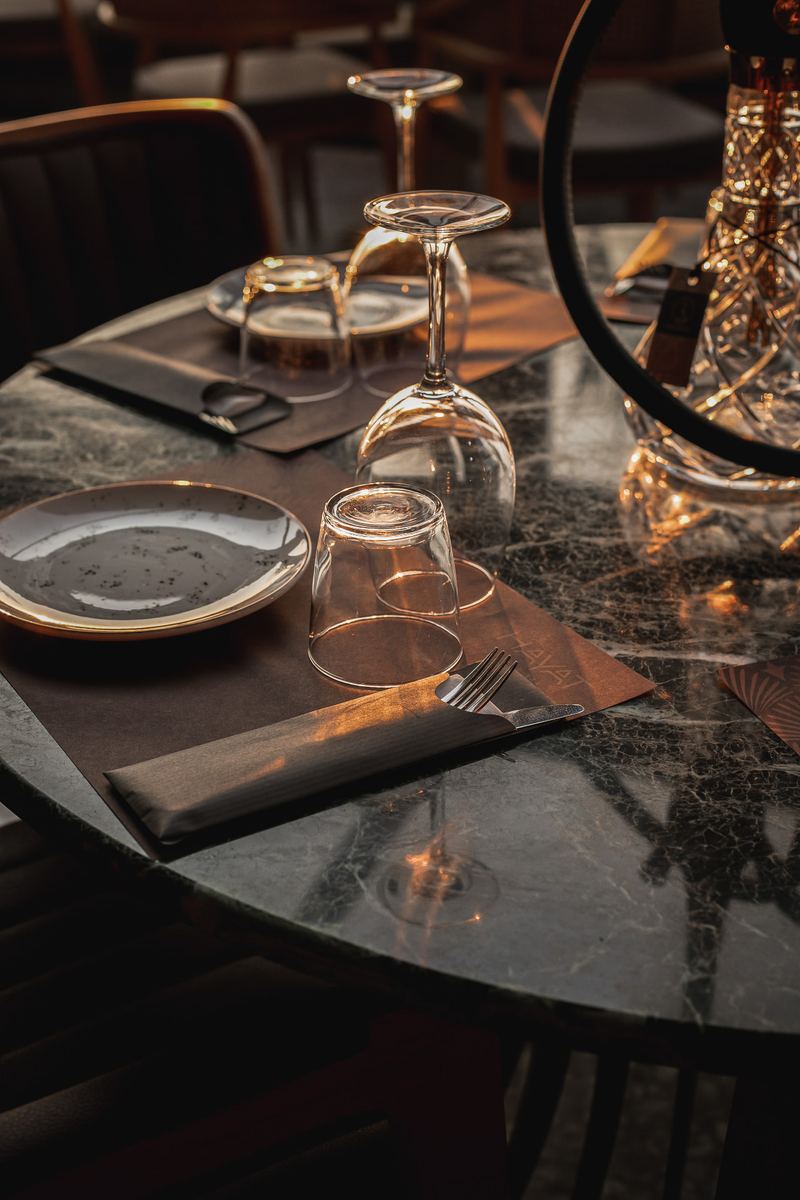 Green marble table set with speckled plates, wine glasses and a crystal shisha catching the last of the sunset light