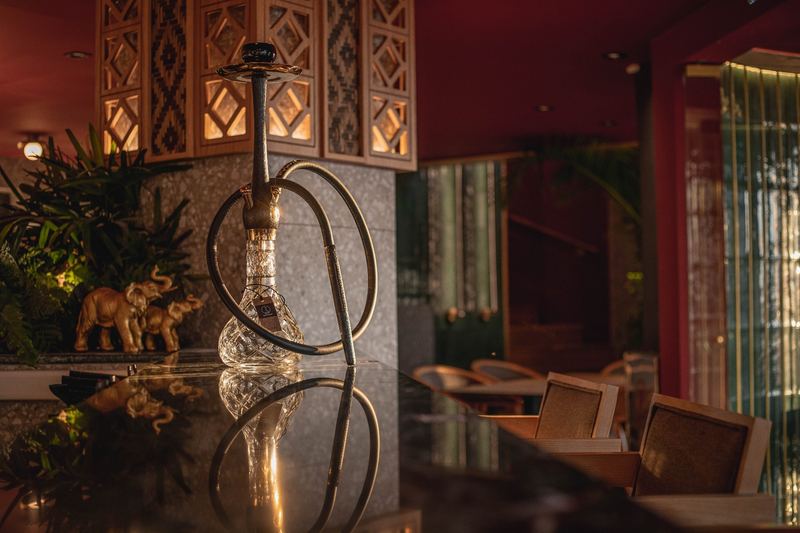 Traditional shisha with a crystal base beside two cocktails on a lounge table
