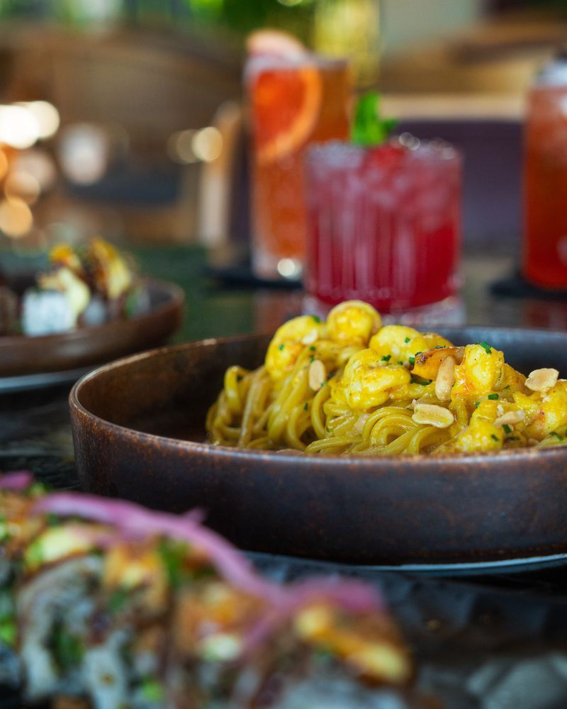 Curry prawn pasta plate paired with two signature cocktails at Al Hayat