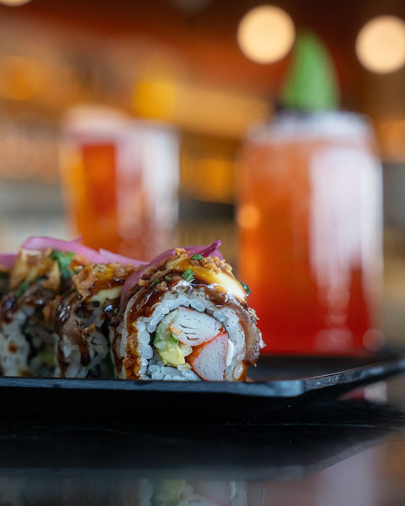 Close-up of nigiri and maki sushi pieces glossed with soy glaze