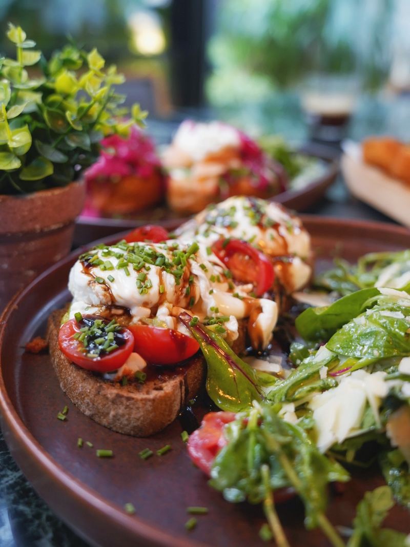 Burrata and cherry tomato bruschetta drizzled with balsamic glaze and chives, served with a rocket and parmesan salad
